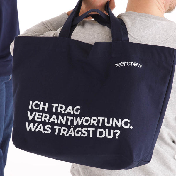Dunkelblaue veercrew Tragetasche "Vessel" mit Schriftzug "Ich trag Verantwortung. Was trägst du?" in Nahaufnahme