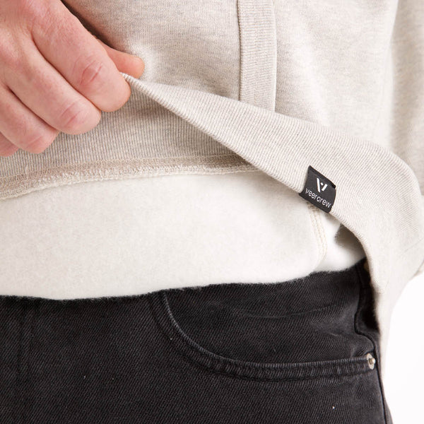 Detailansicht der hellgrau melierten veercrew Hoodie "Armor", Saum leicht angehoben mit Blick auf das Innenfutter und das eingenähte veercrew Label