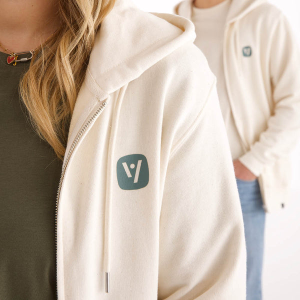 Detailansicht der naturweißen veercrew Zip-Hoodie "Haven" mit Kapuze und Logo-Patch am Reißverschluss