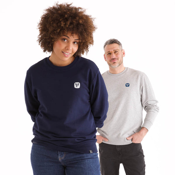 Frau und Mann in veercrew Sweatshirt "Solid", die Frau in Dunkelblau, der Mann in Grau meliert, jeweils mit kleinem Logo-Print
